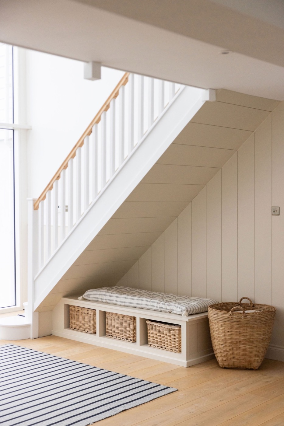 Built-in bench and baskets beneath the staircase