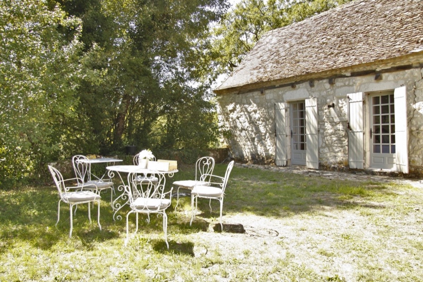Le Petit Capelier’s stone façade and outdoor tables beneath mature trees